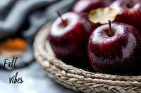 Fresh dark red apples with water droplets in woven basket, creating cozy autumn atmosphere for seasonal food photography and harvest themes.