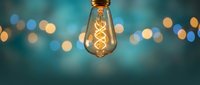 Vintage Edison bulb with glowing filament against blurred bokeh lights background. Creative inspiration and innovation concept for modern interior design.