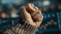 Close-up of clenched fist in knitted sweater sleeve showing determination and strength against blurred urban background for motivation concepts.