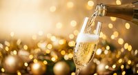 Champagne pouring into elegant flute glass with golden bokeh lights creating festive celebration atmosphere for New Year and special occasions.