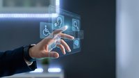 Businessman hand interacting with digital accessibility icons including wheelchair symbol, headphones, and search function for inclusive technology solutions.