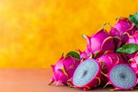 Fresh dragon fruit sliced in half showing vibrant pink skin and white speckled flesh against orange background, tropical exotic produce arrangement.