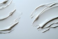 White cream texture with smooth wavy strokes on light background, showing cosmetic product consistency and luxurious skincare moisturizer spread pattern.