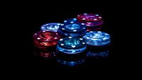Glowing casino poker chips in blue and red colors on black background with reflective surface, used for gambling and gaming concepts.
