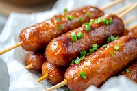Grilled sausages on wooden skewers with fresh herbs, barbecue food ready to serve at outdoor cooking event or restaurant menu.