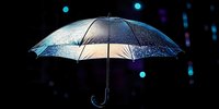 Transparent umbrella with glowing light particles falling against dark background, suitable for weather, protection, and digital design concepts.