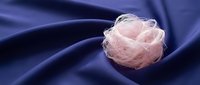 Pink delicate rose flower on flowing navy blue silk fabric with soft folds, suitable for luxury beauty, wedding, and cosmetics design projects.