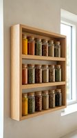 Wooden wall-mounted spice rack with glass jars containing various dried herbs, spices, and seasonings organized on three shelves near a bright window for kitchen storage.