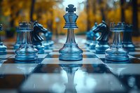 Glass chess pieces on board with king in focus against autumn background, dramatic lighting creates reflections on glossy surface. Strategic game concept.