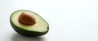 Fresh ripe avocado half with pit on clean white background, healthy organic fruit isolated for cooking and nutrition concepts.