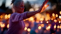 Mature woman with outstretched arms against glowing bokeh lights background at dusk, creating magical atmosphere of freedom, joy and celebration. Soft focus effect.