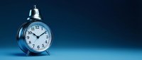 Classic silver alarm clock with white face showing ten past ten on blue gradient background with copy space for time management concepts.