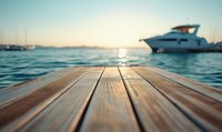 Wooden pier deck close-up with blurred luxury yacht and calm ocean water at sunset. Selective focus on textured boardwalk planks creates dreamy summer marine atmosphere.