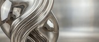 Abstract metallic sculpture with flowing curves and reflective chrome surface creating elegant modern art piece for contemporary interior design.
