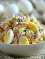 Fresh tuna salad with hard boiled eggs and green onions served in white bowl, ready to eat healthy protein meal for lunch or dinner preparation.