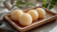 Traditional Asian steamed buns with sesame seeds on wooden tray, soft white dumplings ready for dim sum breakfast or lunch meal preparation.
