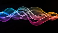Colorful flowing waves with smooth gradient transitions from blue to orange on black background for modern digital design and technology concepts.