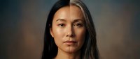 Professional portrait of confident Asian businesswoman with long dark hair against blurred background for corporate marketing and business presentations.