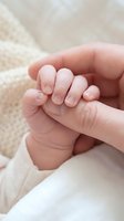 Tiny newborn hand gently gripping an adult finger, symbolizing love, trust, and the bond between parent and child.