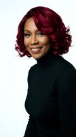 Professional African American woman with burgundy curly hair wearing black turtleneck smiling confidently on white background for business portraits.