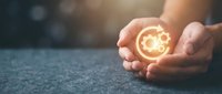 Hands holding glowing gear symbol representing innovation, technology, and business solutions for corporate growth and digital transformation concepts.