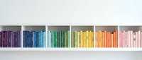 Colorful books arranged by rainbow spectrum on white bookshelf creating organized library display for home decor and educational concepts.