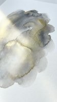 Abstract watercolor wash in muted gray and gold tones creating organic flowing shapes on white paper background for artistic projects and creative designs.