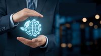 Businessman in dark suit holding glowing globe icon between hands, representing global business, international commerce, and worldwide digital connectivity in modern corporate environment.