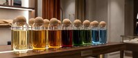 Colorful liquid samples in glass bottles with cork stoppers arranged in gradient spectrum on wooden table, suitable for cosmetics, perfume, essential oils, or laboratory testing.