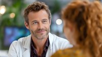 Confident middle-aged Caucasian businessman with stubble and casual attire smiling warmly during office meeting conversation with colleague. Professional workplace interaction.