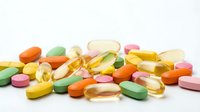 Colorful assorted pills, capsules and tablets scattered on white background for healthcare, pharmacy and medical supplement concepts.