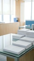 Stacks of white paper documents organized on glass desk in modern bright office workspace for business administration and paperwork management.