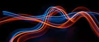 Glowing neon light trails in blue and red flowing across dark background, creating smooth wave patterns for digital design and motion graphics projects.