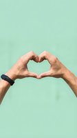 Hands forming a heart shape against a mint green background, wearing a fitness tracker, symbolizing love, health, and wellness.