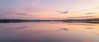 Serene lake at sunset with pink and purple sky reflecting on calm water surface, peaceful nature landscape for relaxation and meditation projects.