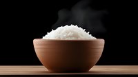Steaming hot white rice served in traditional clay bowl on wooden surface against black background, dramatic food photography with rising steam.