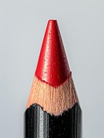 Red glitter sharpened pencil tip with natural wood and black graphite layers visible on neutral background, isolated for design use.