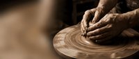 Hands of male artisan shaping wet clay on spinning pottery wheel, traditional ceramic craft technique and handmade pottery creation process.