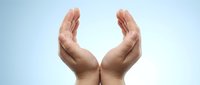 Two open hands positioned protectively around glowing light symbolizing care, protection, support and spiritual guidance for wellness concepts.