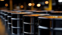 Industrial black metal oil barrels in warehouse storage facility with warm ambient lighting creating professional petroleum industry atmosphere.