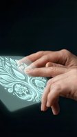 Hands touching holographic display with ornate patterns on dark background for futuristic technology and digital interface concepts.