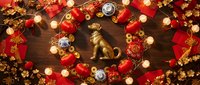 Festive overhead arrangement of red and gold ornaments, lights, and decorative elements on wooden surface for holiday celebrations.
