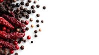 Red dried chili peppers and scattered black peppercorns with fresh cranberries on white background, creating dramatic contrast for food photography and culinary designs.