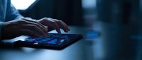 Businessman hands typing on digital tablet with glowing screen in modern office environment for technology and business communication applications.