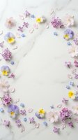 Delicate spring flowers arranged in circular frame on white marble background with copy space for text, wedding invitation or greeting card design.