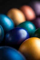 Colorful metallic spheres in vibrant blue, gold, and green tones arranged closely together with soft focus and dramatic lighting creating depth and texture.