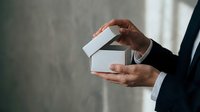 Businessman in formal suit holding white gift box with ribbon, corporate gifting and business presentation concept for holidays and special occasions.