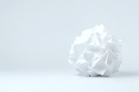 Crumpled white paper ball on light background with copy space, symbolizing creative block, waste, or fresh start in minimalist composition.
