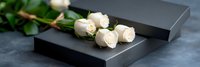 Elegant white roses arranged on sleek black gift boxes creating luxurious romantic composition for special occasions and celebrations.