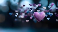 Pink heart floating among scattered purple and blue heart shapes against dark blurred background with bokeh effect, romantic Valentine's day concept for greeting cards.